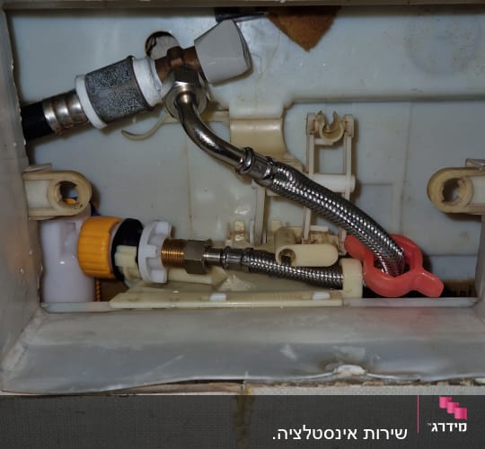 חלקי אינסטלציה בתוך קיר עם צינורות וחיבורים